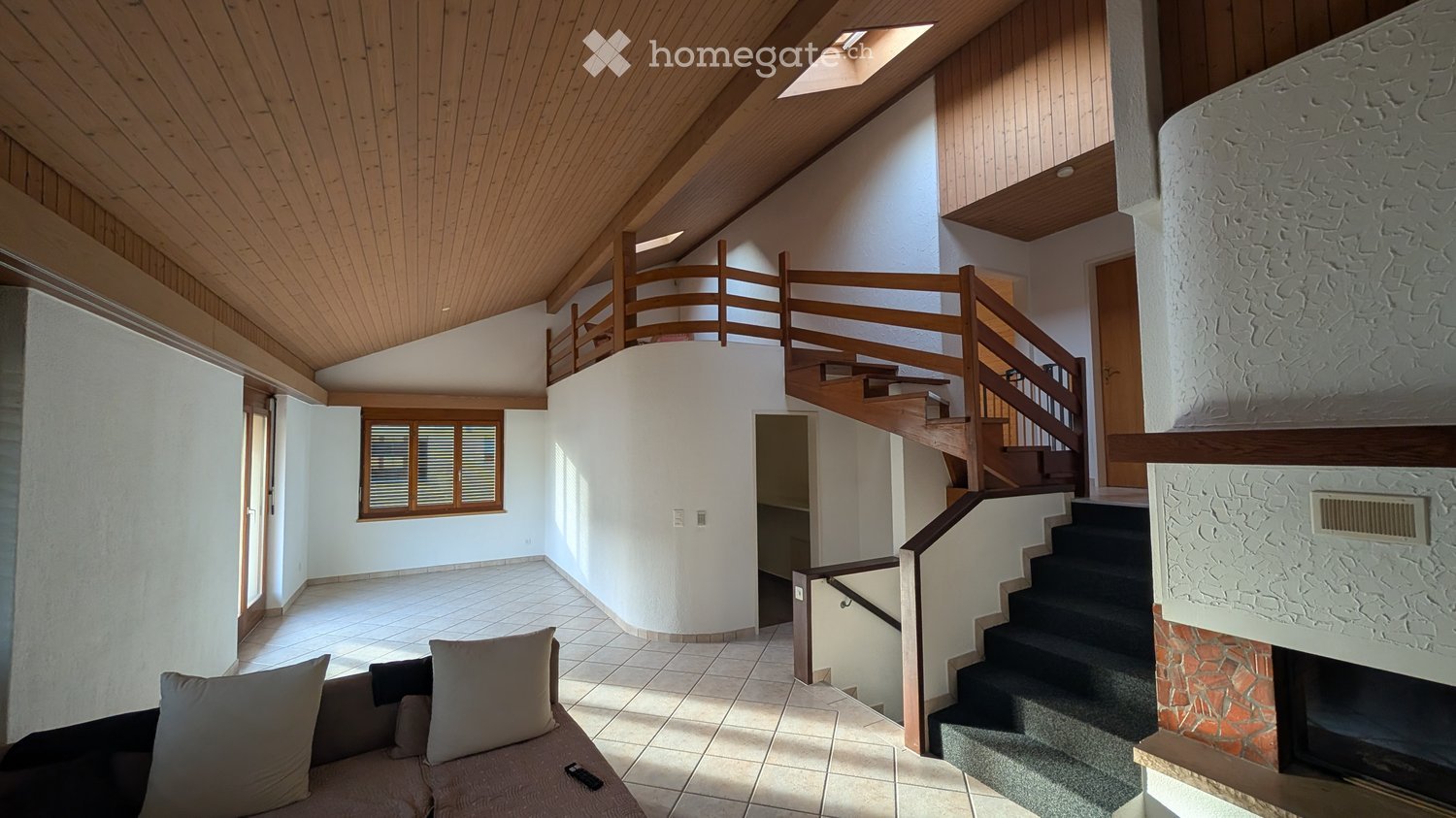 Living room with couch, fireplace, tiled floor, wooden staircase