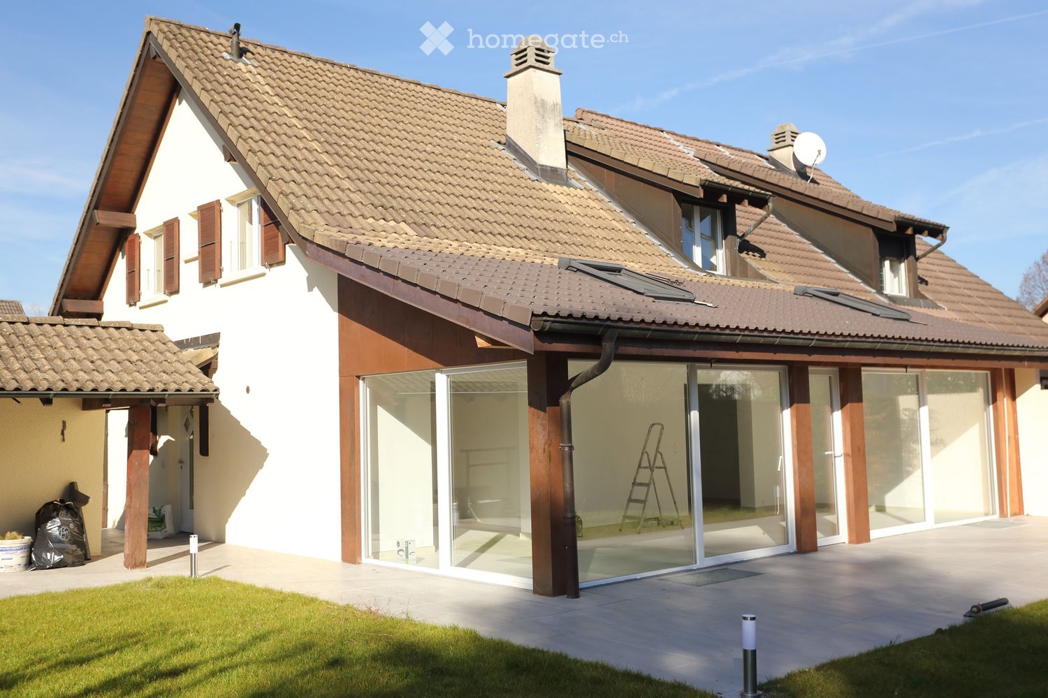 House. Modern house with brown roof, white walls, glass doors and windows, and a patio.