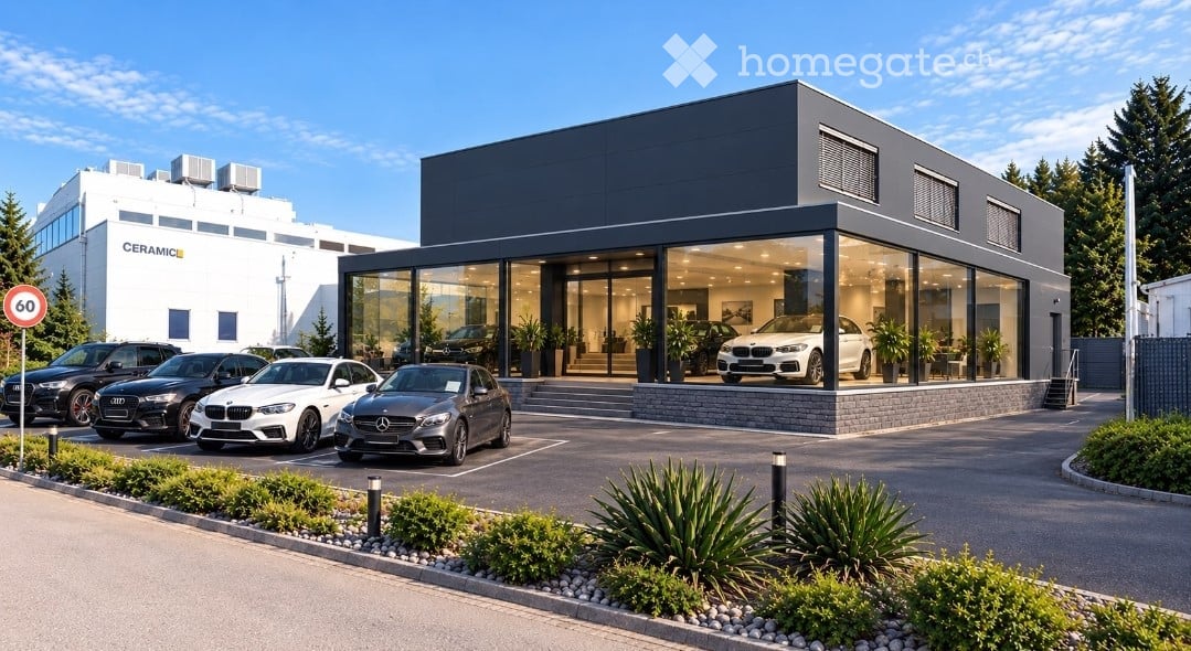 Modern car dealership building with large glass windows, several luxury cars displayed inside and outside, surrounded by landscaped greenery and a paved parking area.