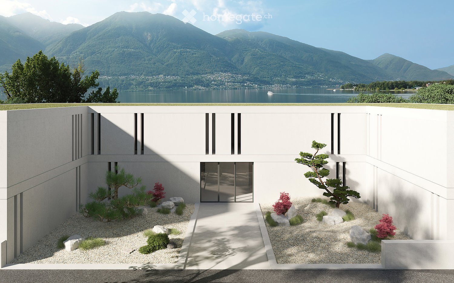 Modern, minimalist house design with a Japanese-inspired garden featuring rocks, plants, and a pathway leading to the entrance. The house has a white exterior with black accents and large windows overlooking a scenic lake and mountain landscape.