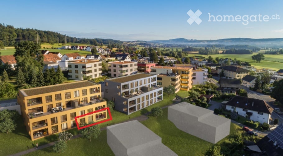 Aerial view of a modern multi-story residential building with balconies and surrounding greenery.