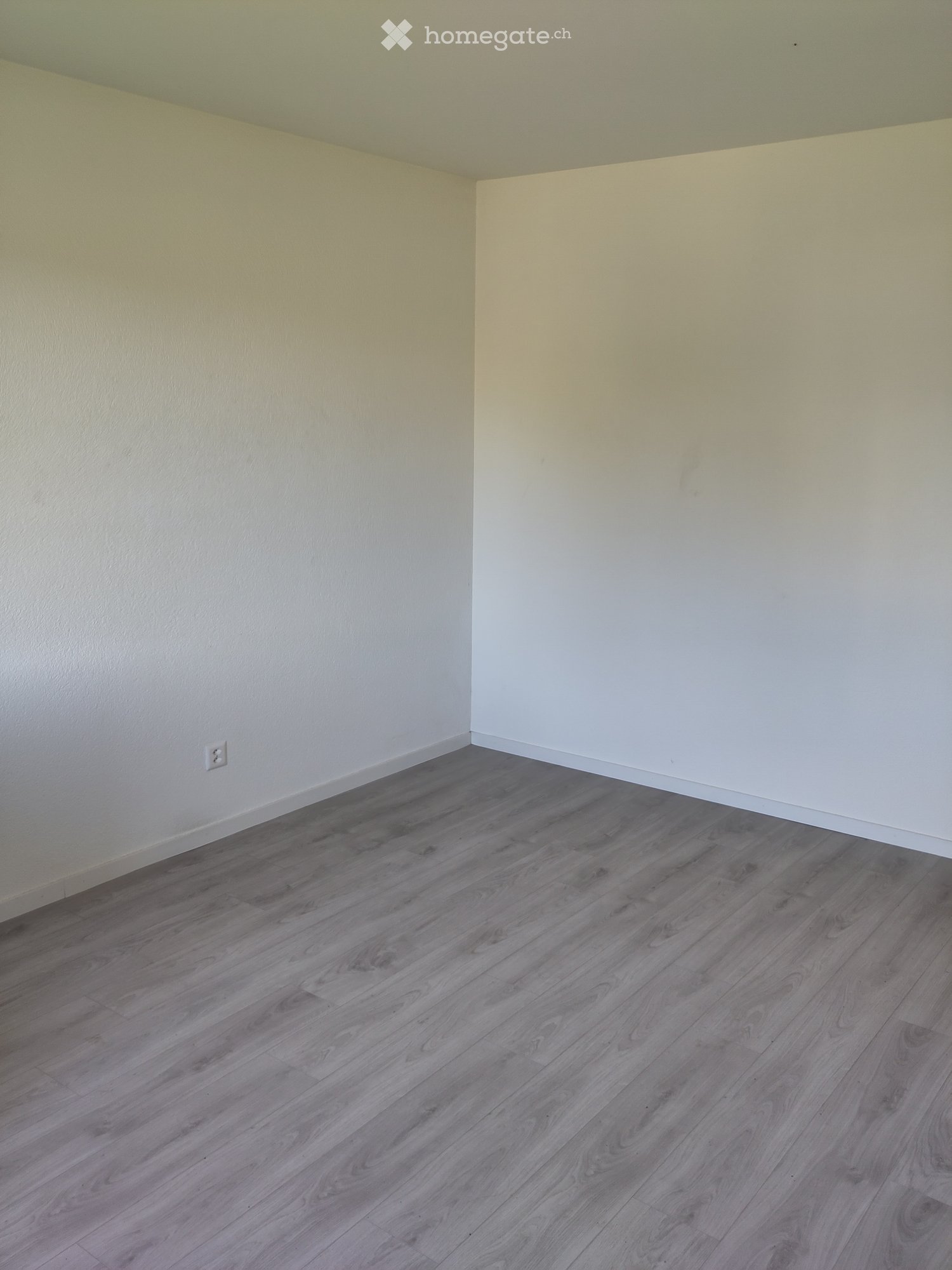 Empty room with light-colored walls and a wooden floor, no furniture or equipment visible.