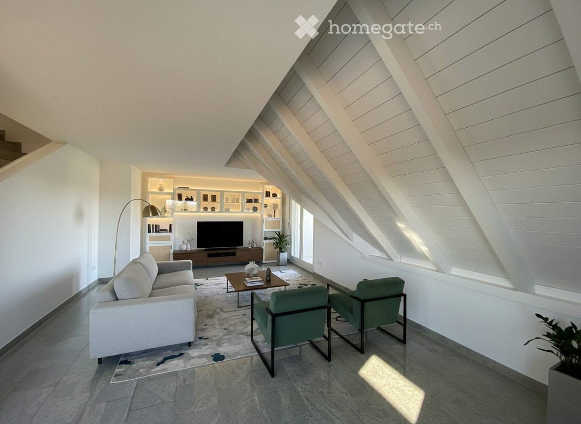 Modern living room with a grey sofa, coffee table, armchairs, television, floor lamp, and built-in shelving unit. The room features a high, slanted ceiling and large windows allowing natural light to fill the space.