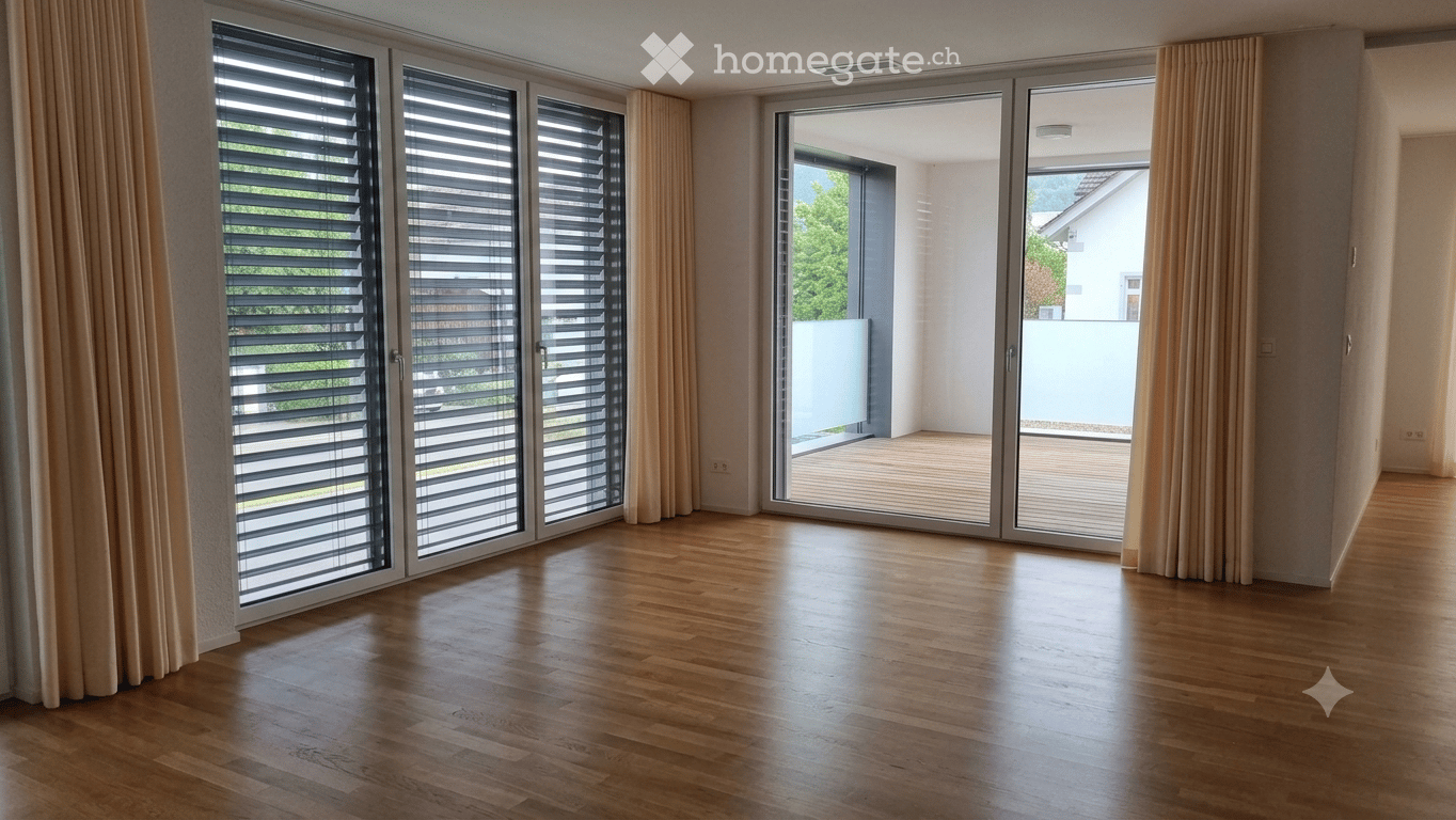 Empty room with wooden flooring, large sliding glass doors with blinds, and light-colored curtains. The space is unfurnished and appears to be a living or dining area.