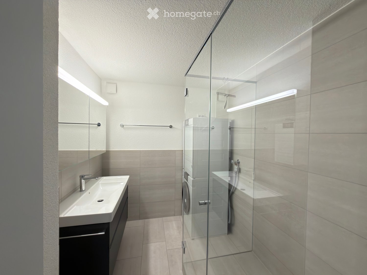 Modern bathroom with a white sink, chrome faucet, mirrored cabinet, and a glass-enclosed shower stall.