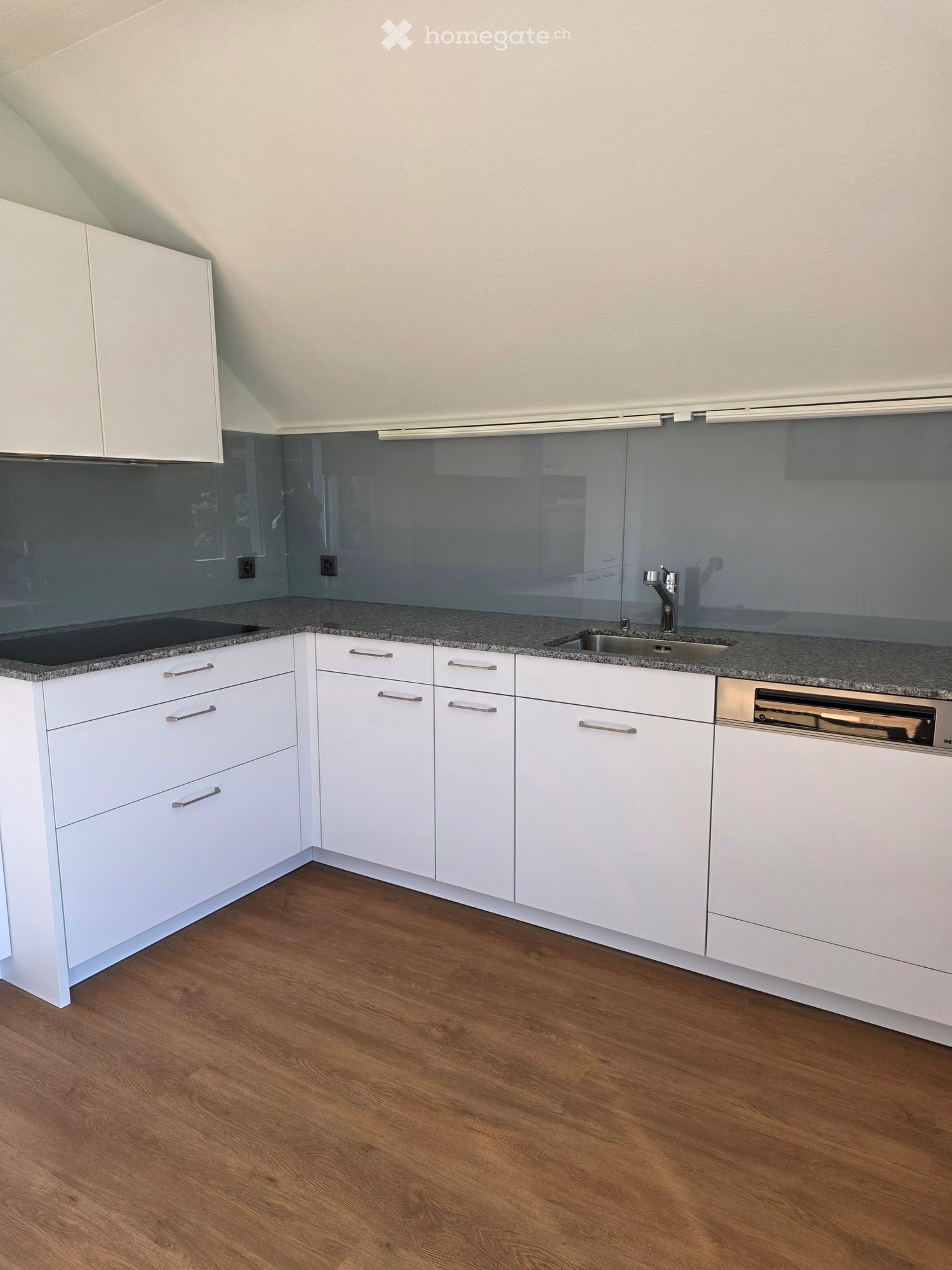 Modern kitchen with white cabinets, granite countertops, and a stainless steel sink and dishwasher.