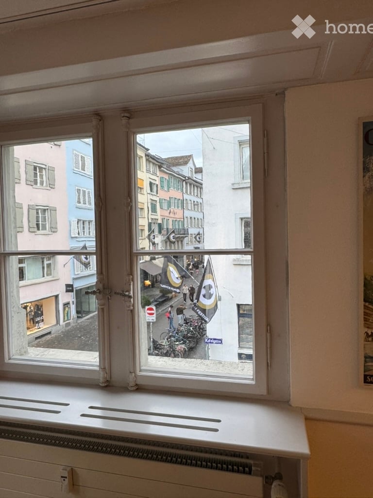 View from a window showing a street scene with colorful buildings, bicycles, and pedestrians.