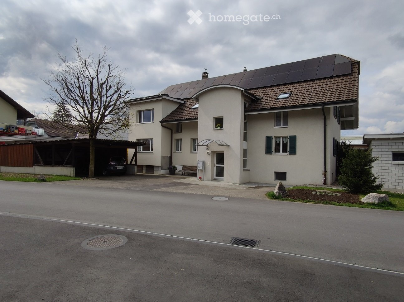 Two-story house with a garage, solar panels on the roof, and a driveway.