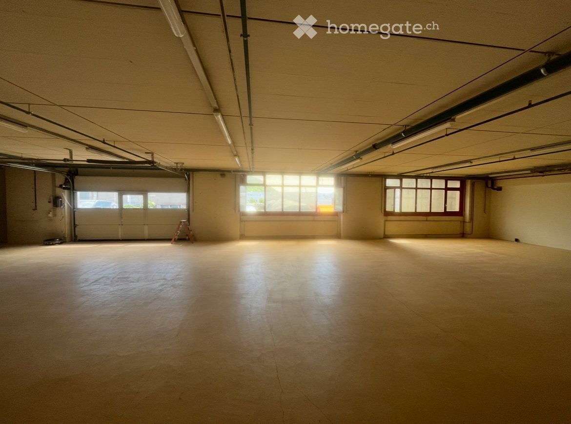 Empty room with bare walls, concrete floor, and large windows allowing natural light. No furniture or equipment present.