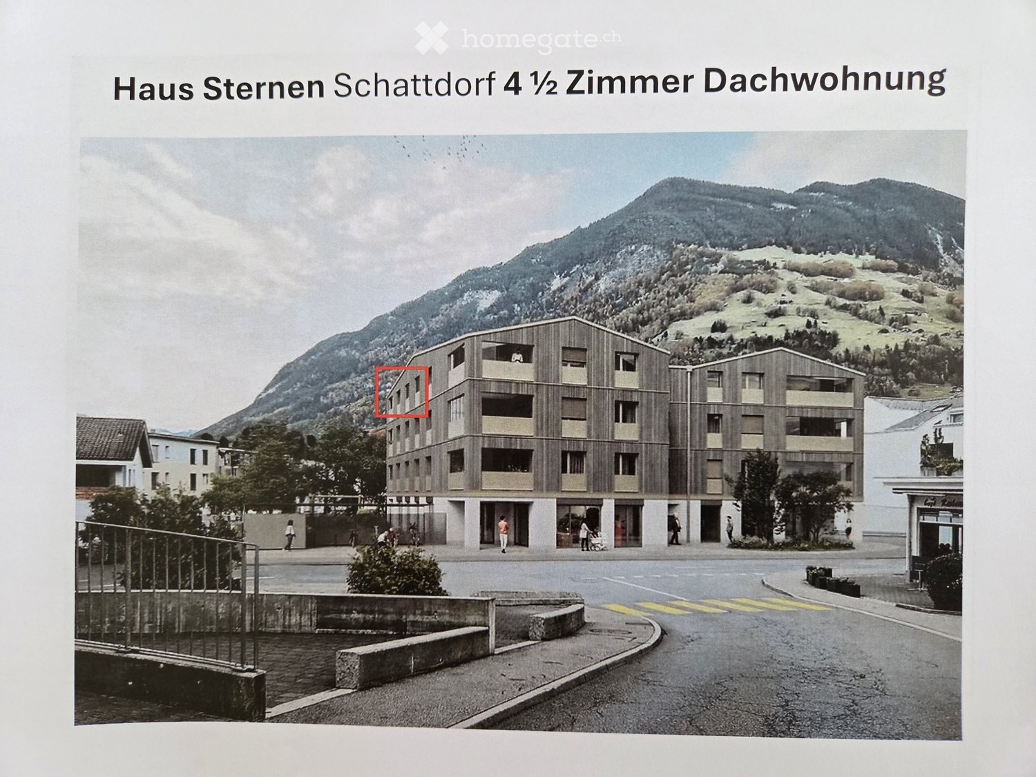 A modern multi-story building with wooden facade and balconies, situated in a scenic mountainous area with a road in front.