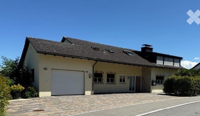 Two-story house with a garage, beige exterior, dark roof, and multiple windows.
