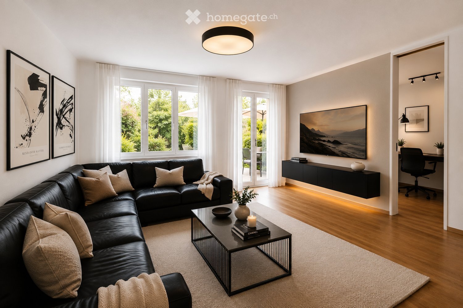 Modern living room with a black leather sectional sofa, a glass coffee table, a TV screen, and a desk area with a chair.