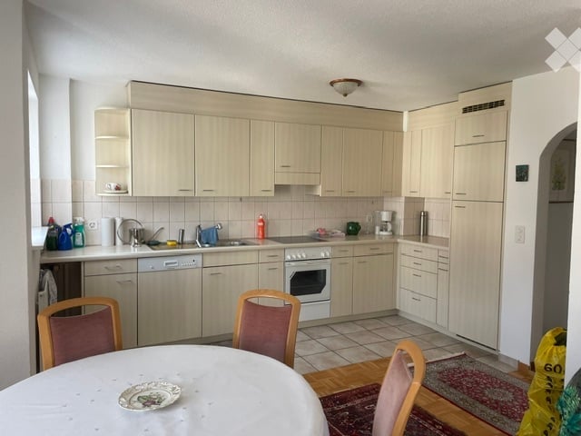 Bright kitchen with light wood cabinets, stainless steel appliances, and a small dining area with a table and chairs.