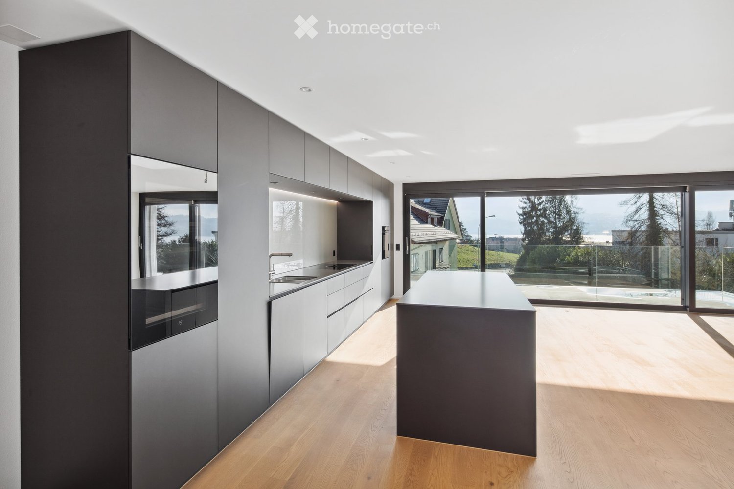 Modern kitchen with sleek cabinetry, a central island, and large windows offering a scenic view.