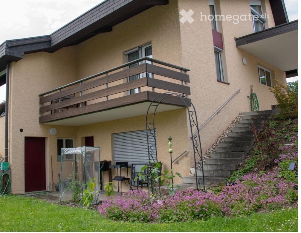 Detached house, beige wall, brown balcony, red door, white shutters, red door, shrubs, garden area