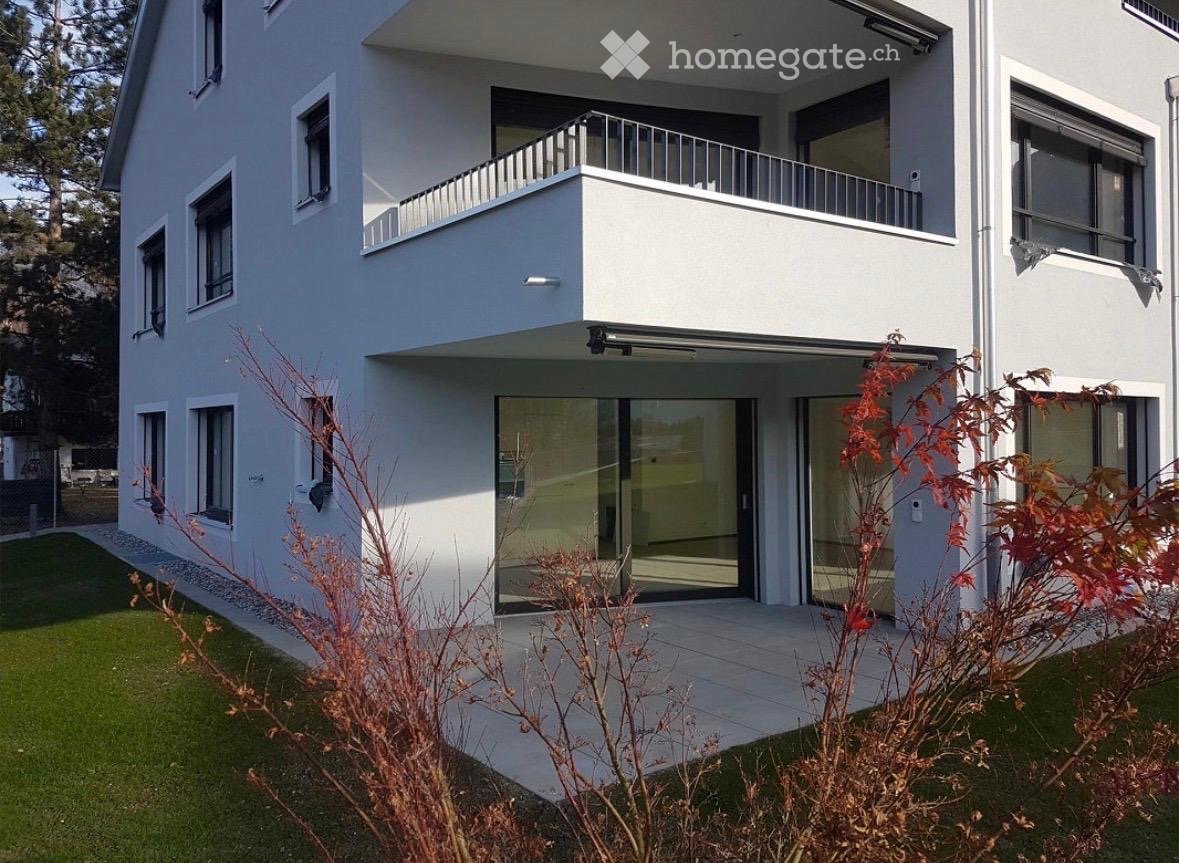 Modern two-story house with white exterior, large windows, and a balcony on the upper level.