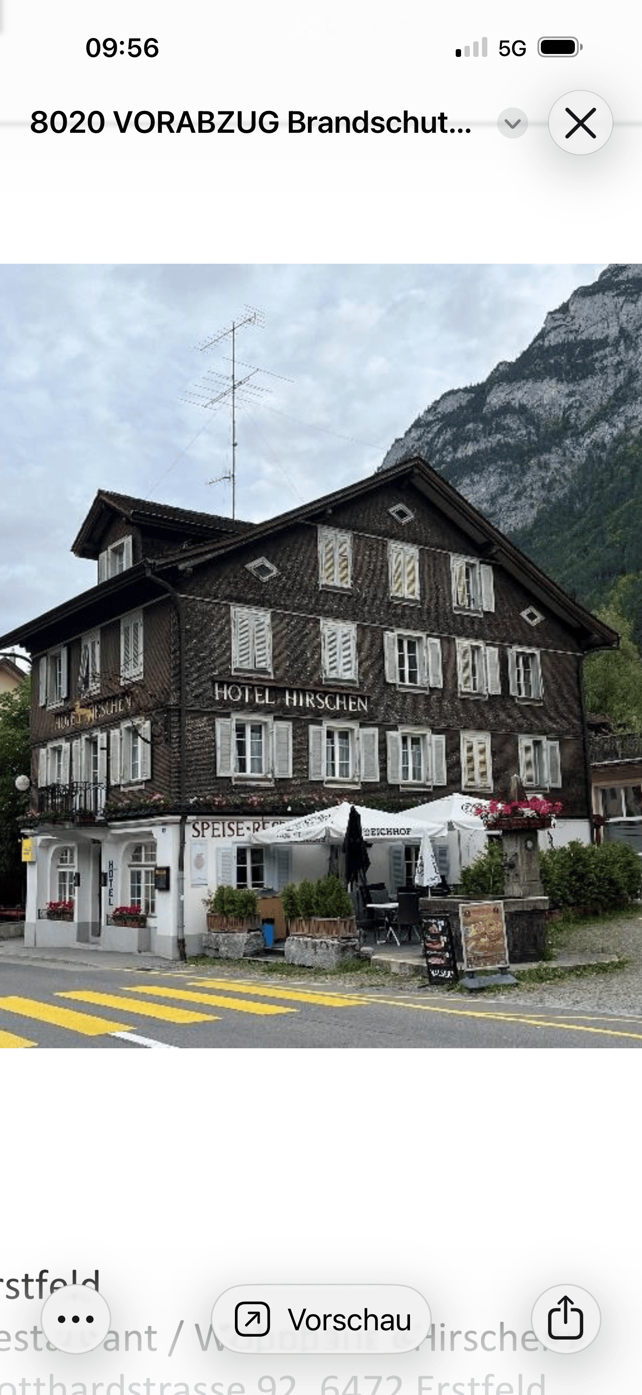 Traditional wooden hotel with multiple windows, balconies, and outdoor seating area with tables and chairs.