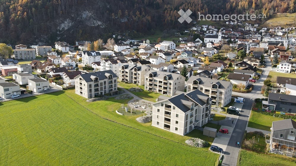 Aerial view of a residential area with multiple apartment buildings, houses, and green spaces.