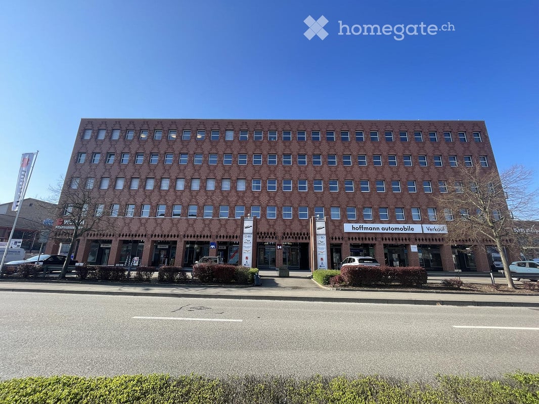 Multi-story brick building with numerous windows and commercial signage for "hoffmann automobile" visible on the ground floor.