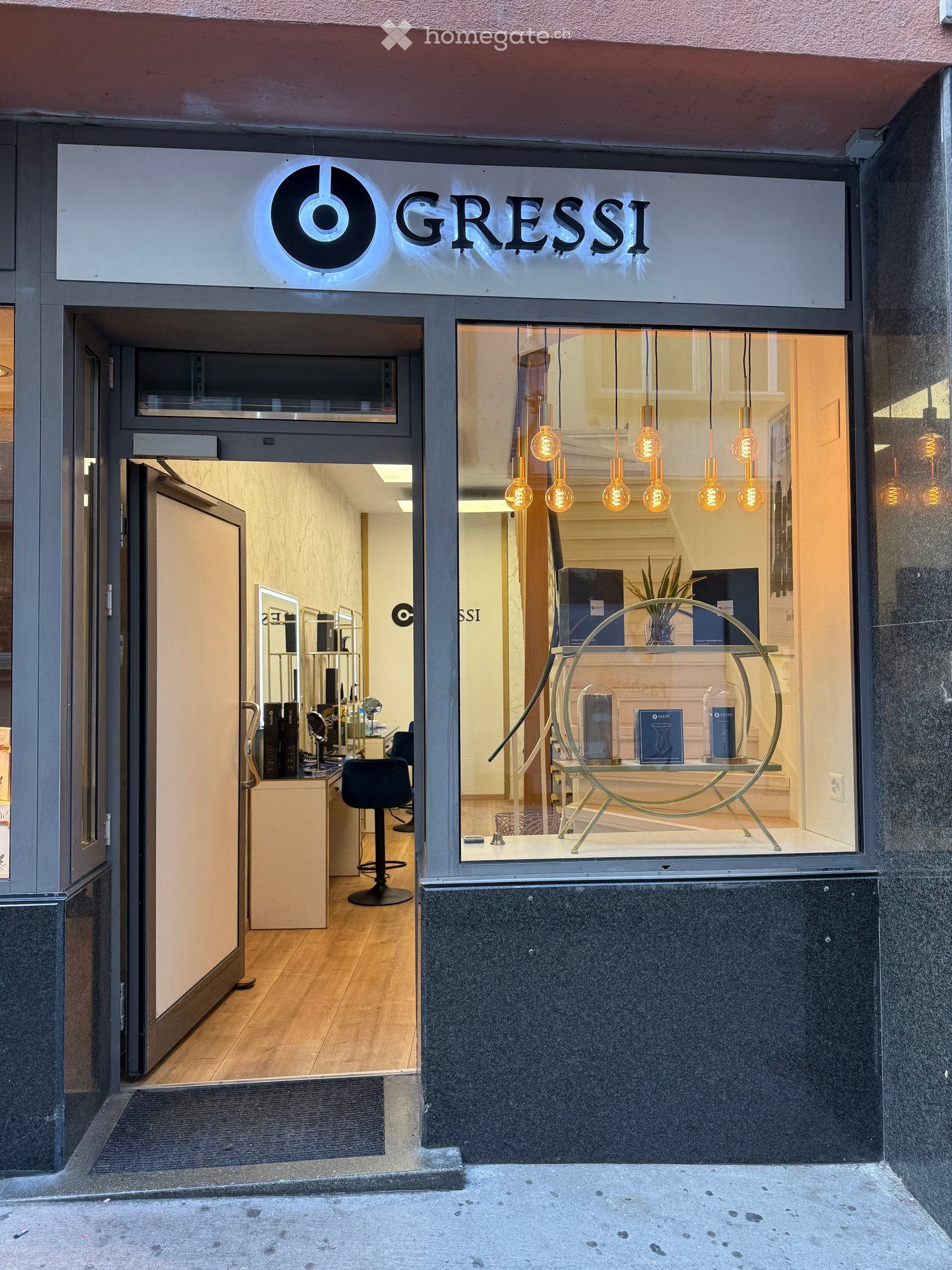 Storefront of "Gressi" with glass display window, interior visible with hanging lights, display table, and seating area.