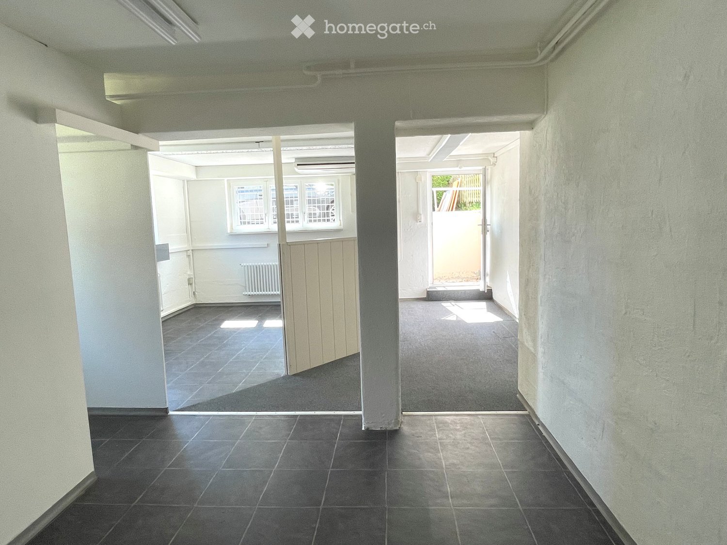 Empty hallway with tiled floors, white walls, and two open doorways leading to adjacent rooms.