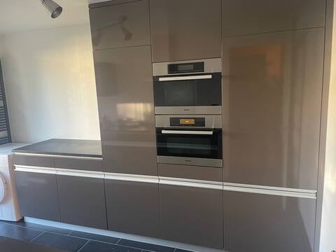 Modern kitchen with sleek grey cabinetry, built-in oven and microwave, and a clean, minimalist design.