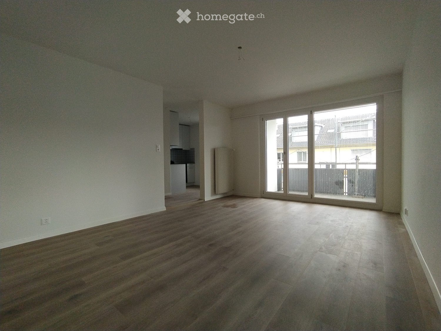 empty room with hardwood floors, white walls, large glass sliding doors leading to a balcony