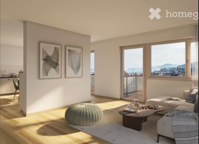 Bright, modern living room with large windows offering a scenic view, featuring a sofa, coffee table, ottoman, round stool, and framed artwork on the wall.