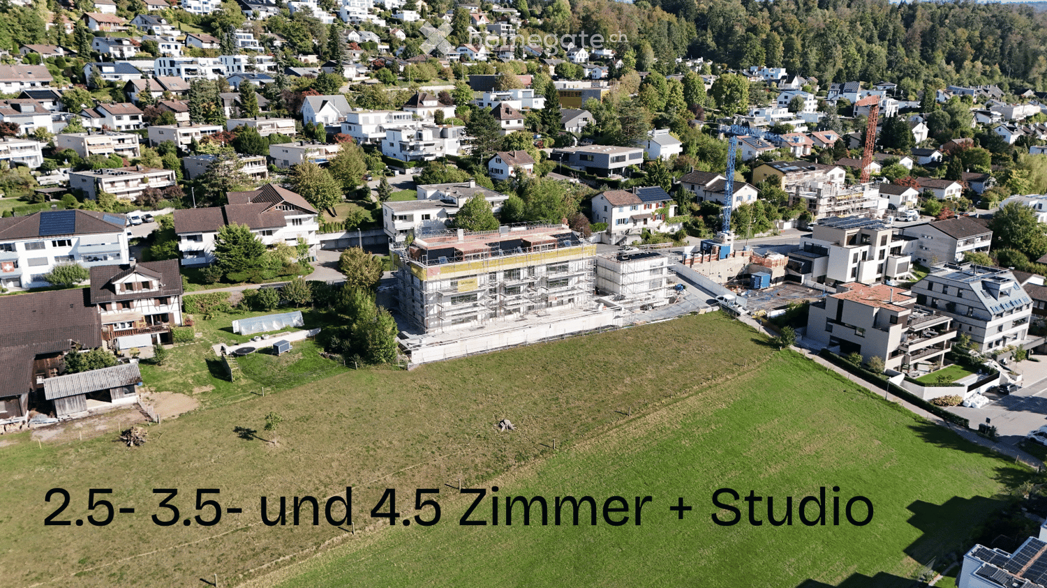 Aerial view of a residential neighborhood with multiple houses, some under construction, surrounded by greenery and trees.