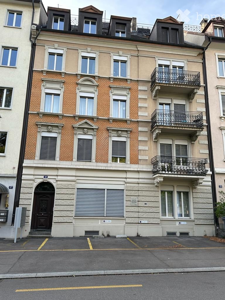 3 story brick building, 3 balconies, white windows, wooden door, 3 parking places, brick ground floor