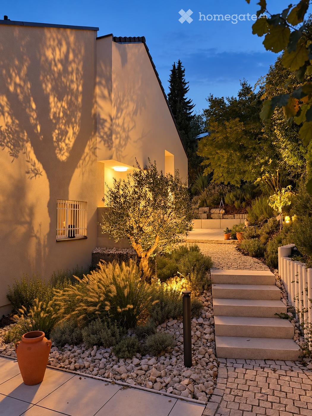 Evening garden scene with a modern house, steps leading up, various plants, and decorative lighting.