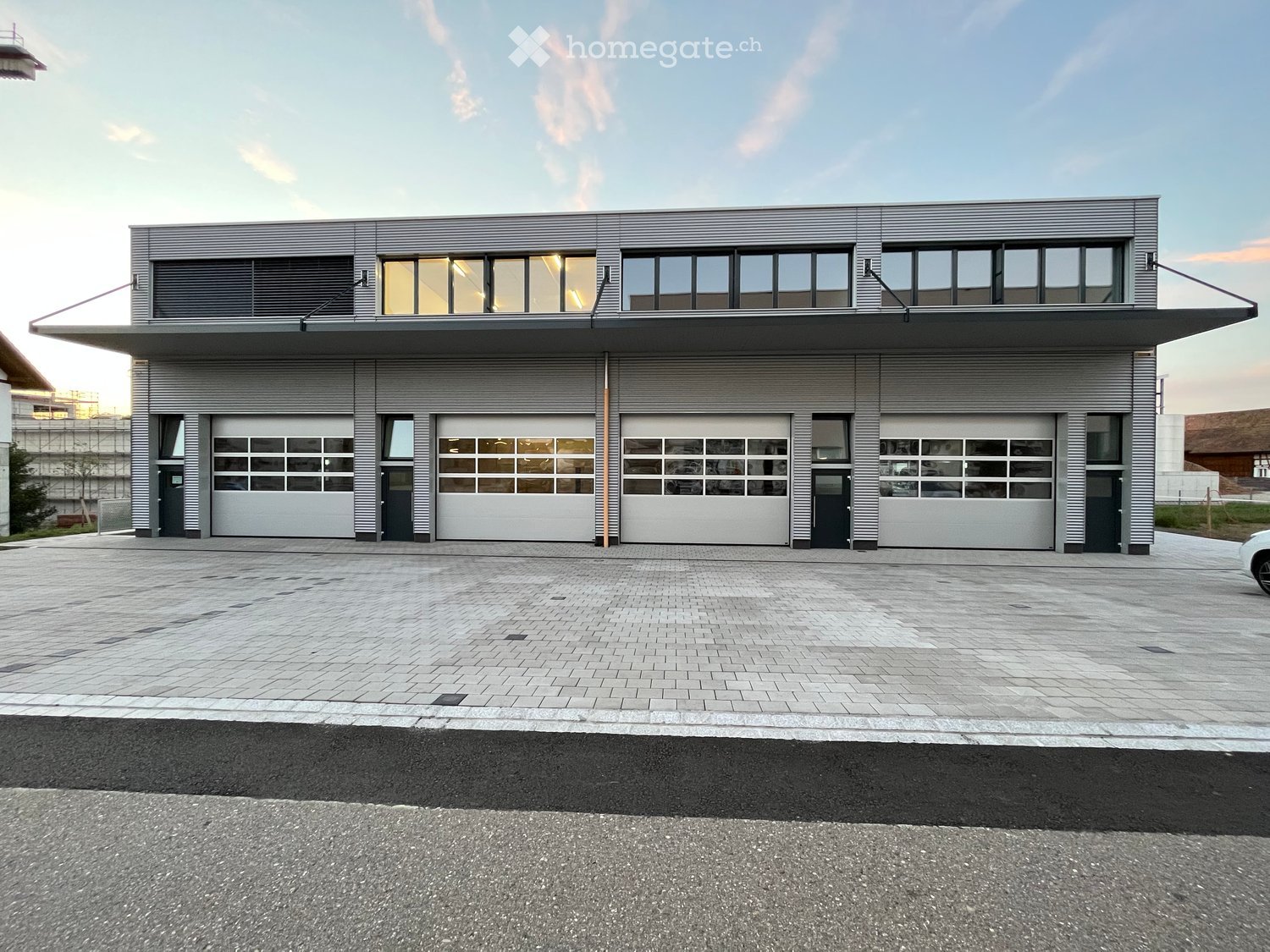 Modern two-story building with large garage doors and large windows on the upper level.