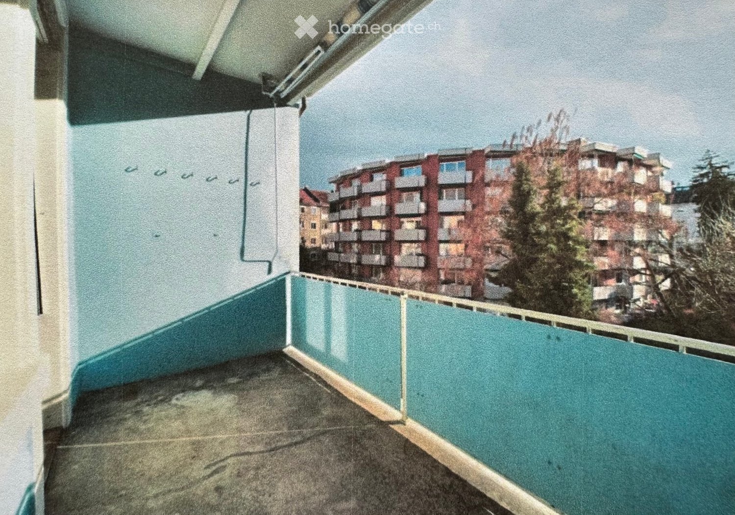 Balcony with a metal railing and a view of surrounding buildings and trees.