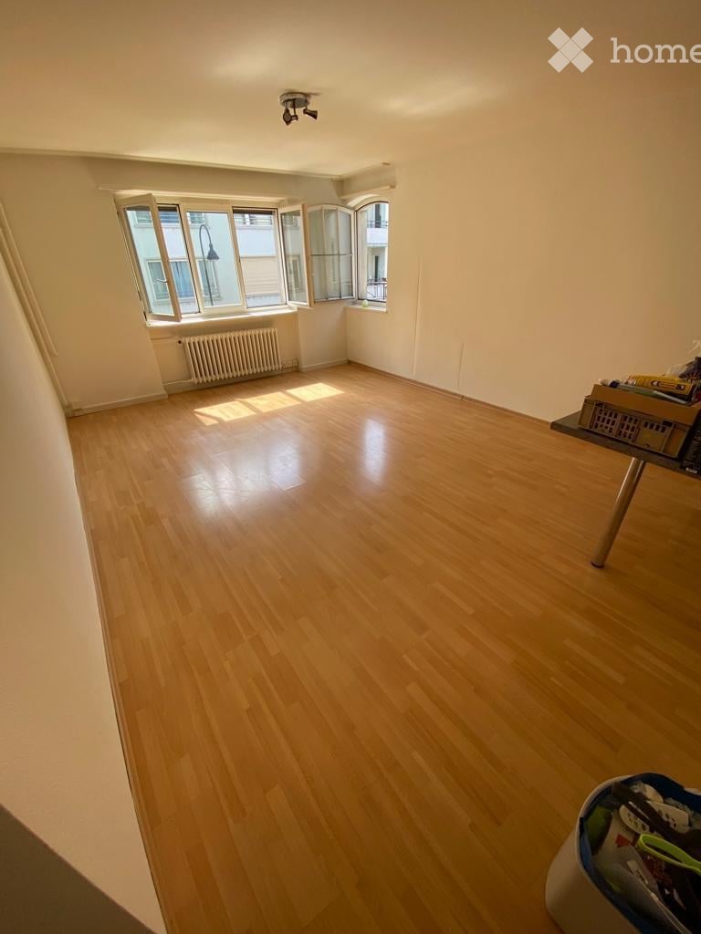 Empty room with wooden flooring, large windows, and a radiator. No furniture or equipment present.