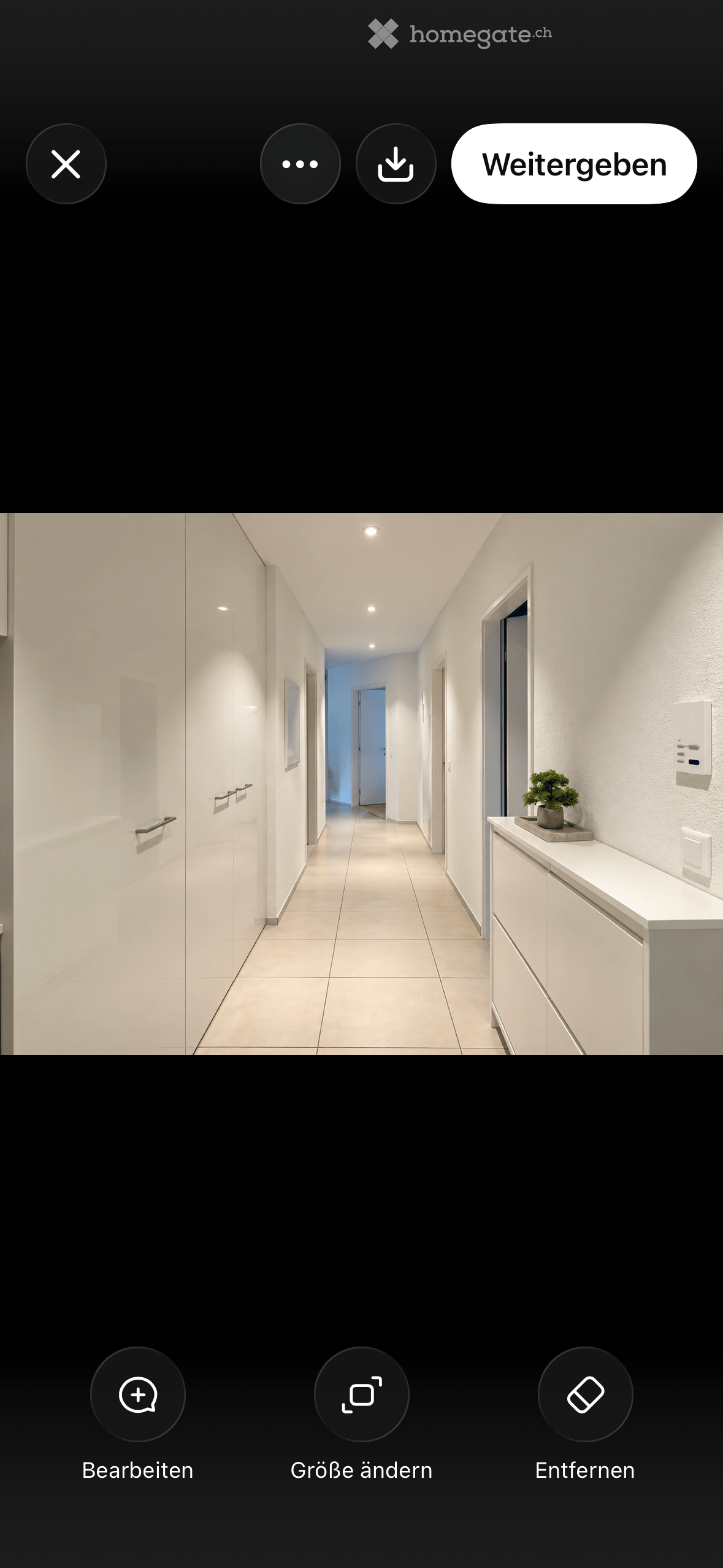 Modern hallway with white walls, tiled floor, recessed lighting, and a small plant on a cabinet.