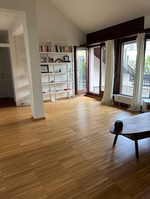 Bright, open room with wooden flooring, large windows, and built-in shelving unit. No furniture present.