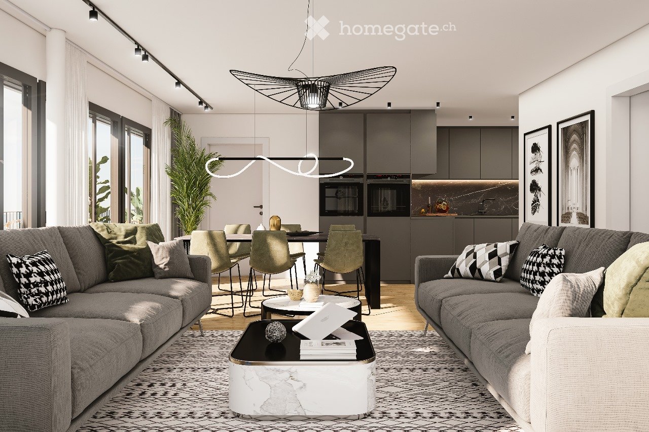 Modern living room with grey sofas, coffee table, dining area with chairs and table, pendant lights, and framed pictures on the wall.