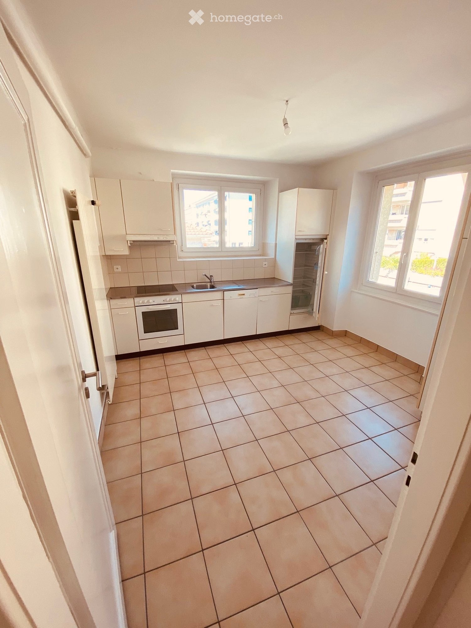 Modern kitchen with white cabinets, tiled floor, and built-in appliances including a refrigerator, oven, sink, and dishwasher.
