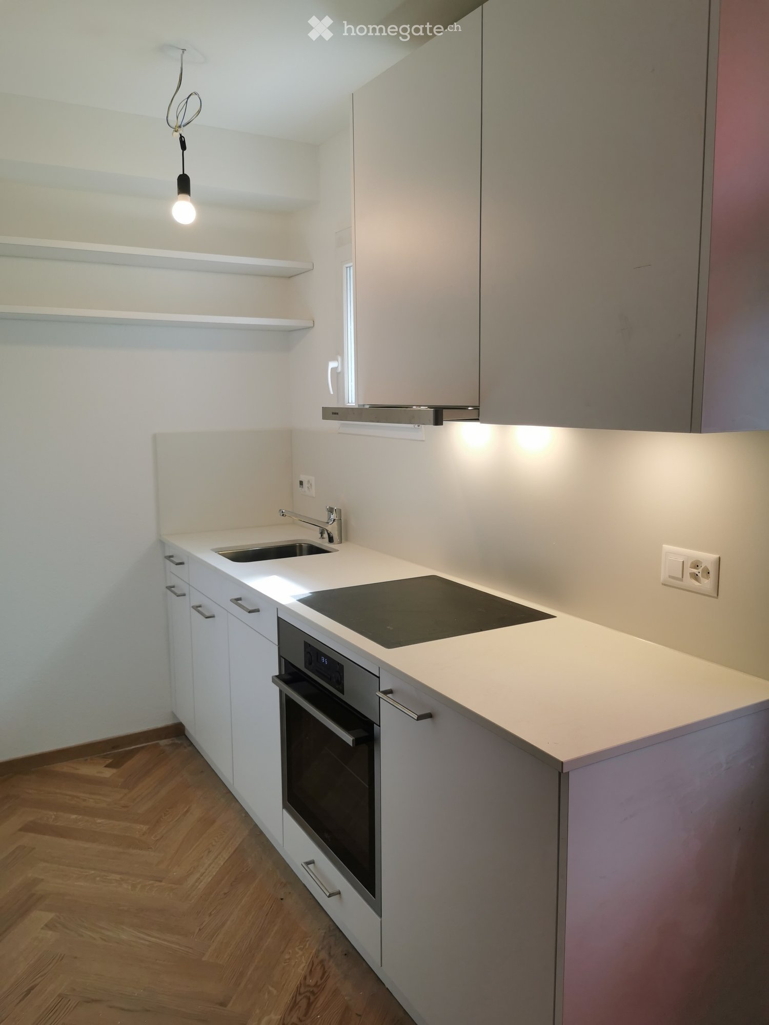 Modern kitchen with white cabinets, a sink, an oven, an induction cooktop, and built-in lighting.