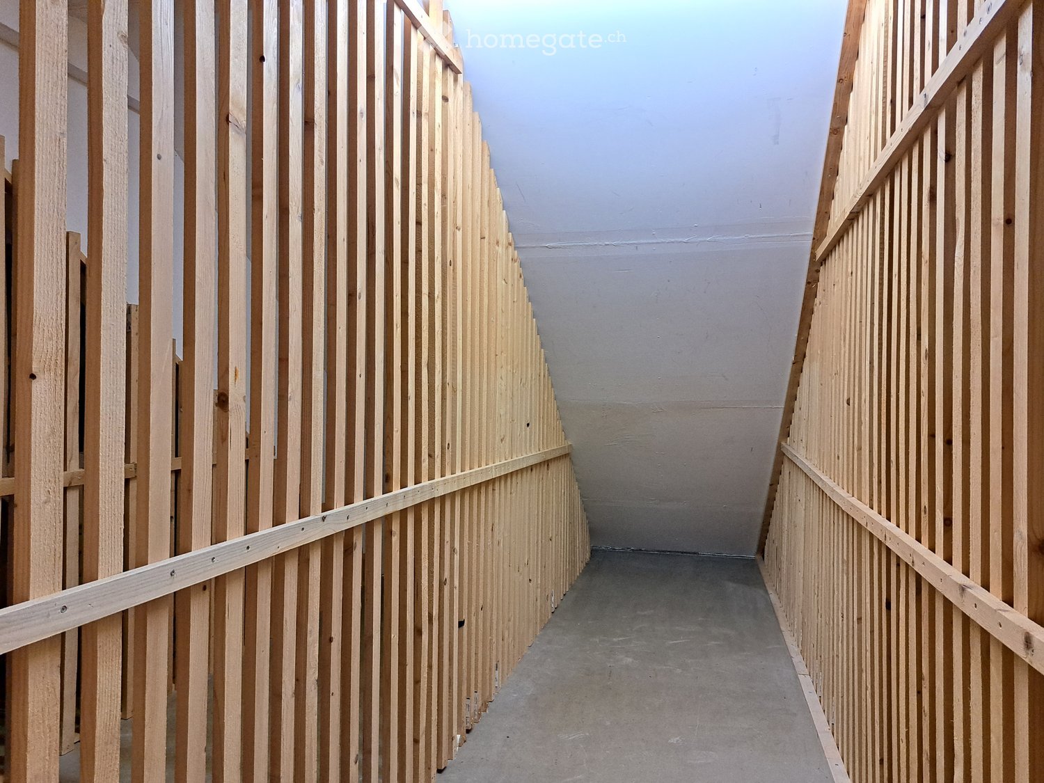 Empty hallway with wooden panel walls and a concrete floor, featuring a simple, modern design with no visible furniture or decorations.