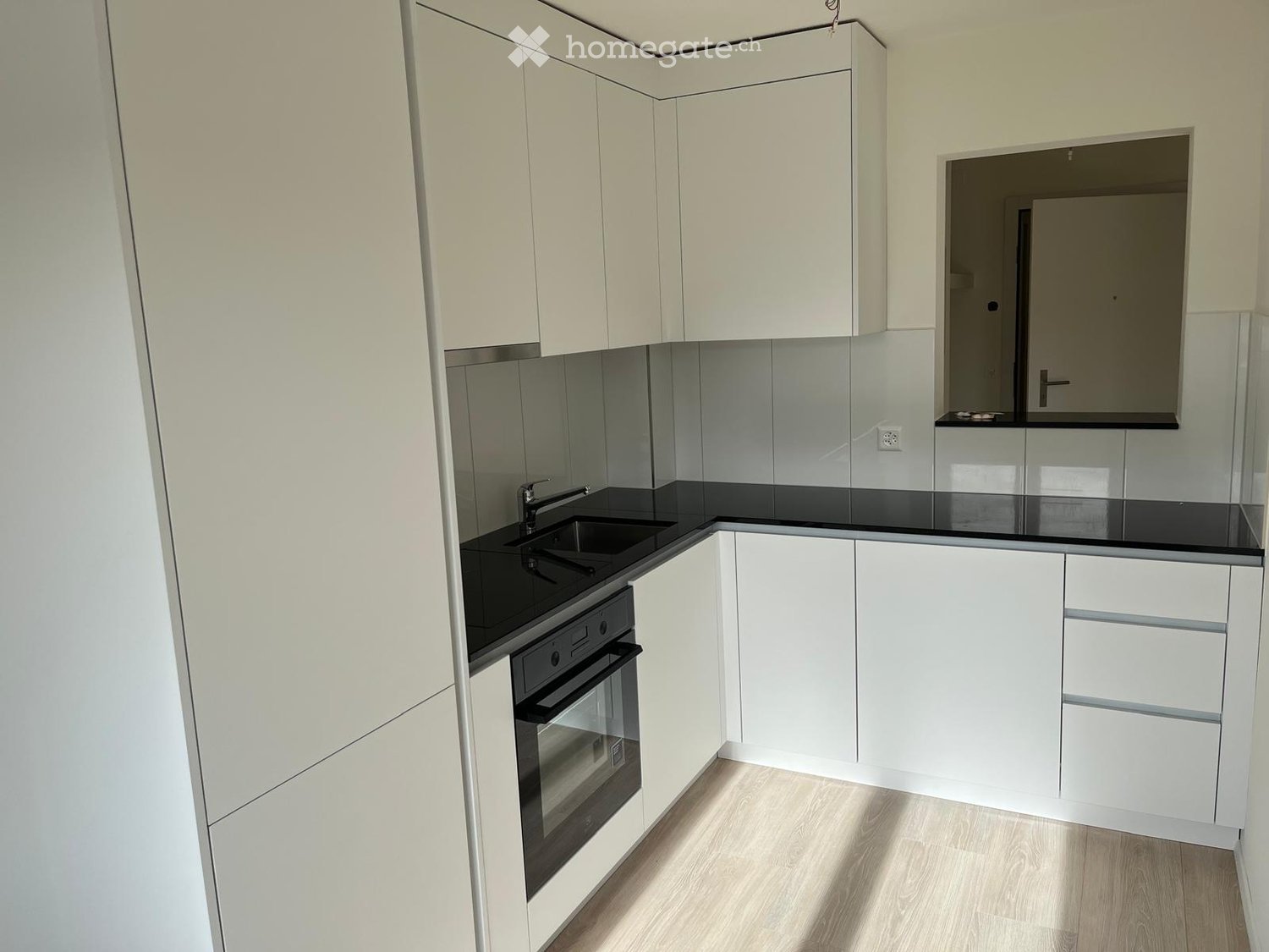 White cabinetry, black countertop, modern appliances, wooden floor