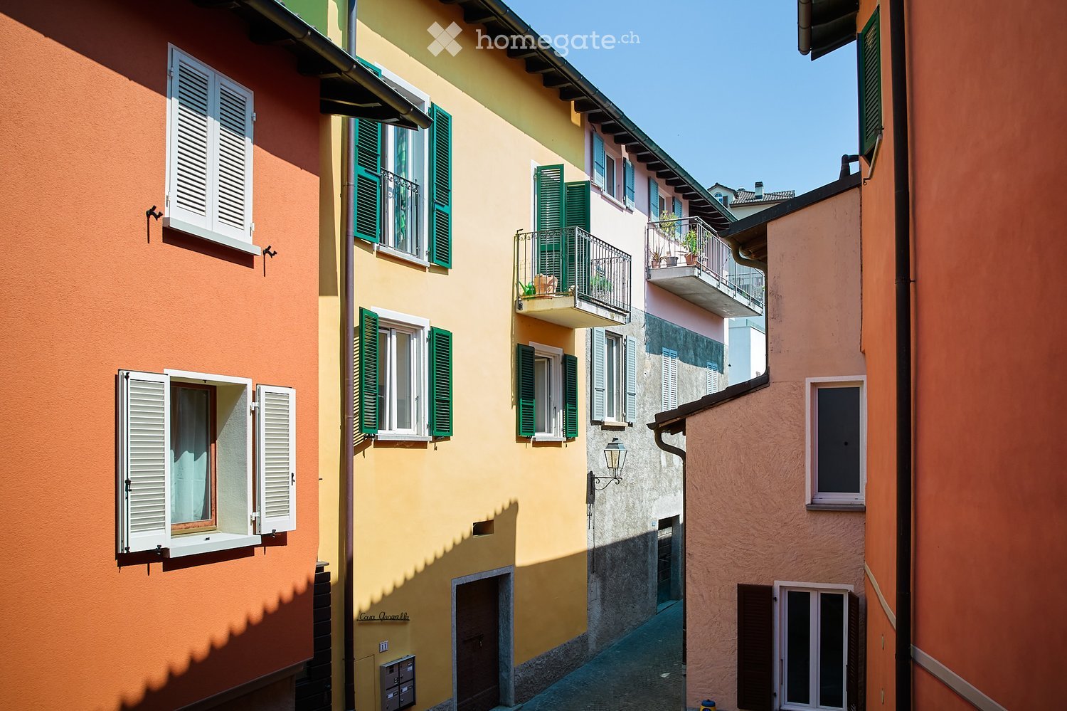 Terraced buildings, multiple colors, balconies with plants, windows with shutters