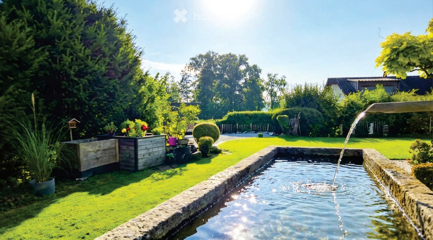 Well-maintained garden with a water fountain, neatly trimmed lawn, various plants, and trees.