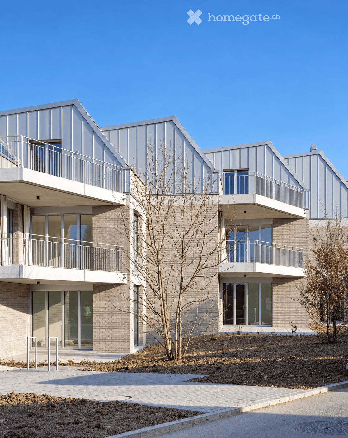 Modern two-story building with a combination of brick and metal exterior, featuring large windows and balconies.