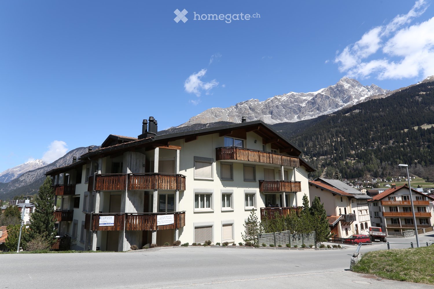 3 story building, white exterior, wooden balconies, mountain view