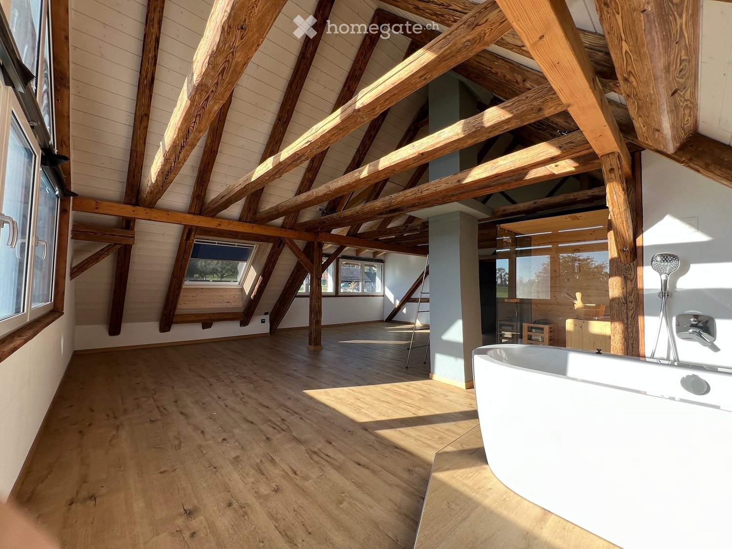 Bathroom with wooden beams, wooden floor, large bathtub, and a small wooden stool.