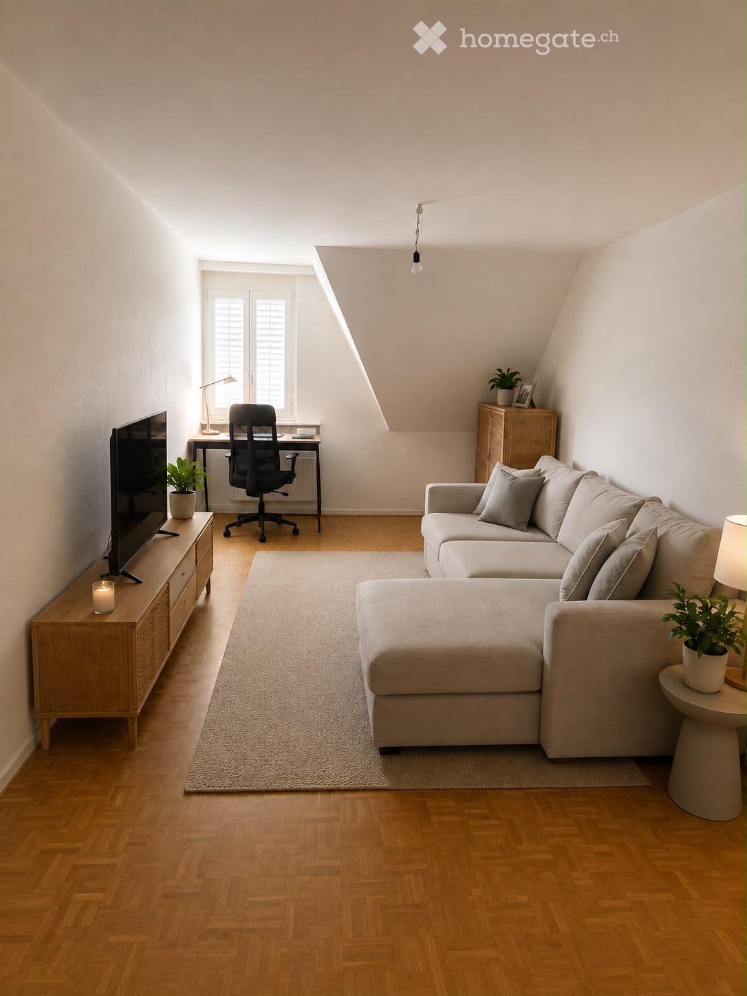 A modern living room with a sectional sofa, coffee table, desk, chair, and a TV stand with a screen. The room features wooden flooring, a large window, and several plants.