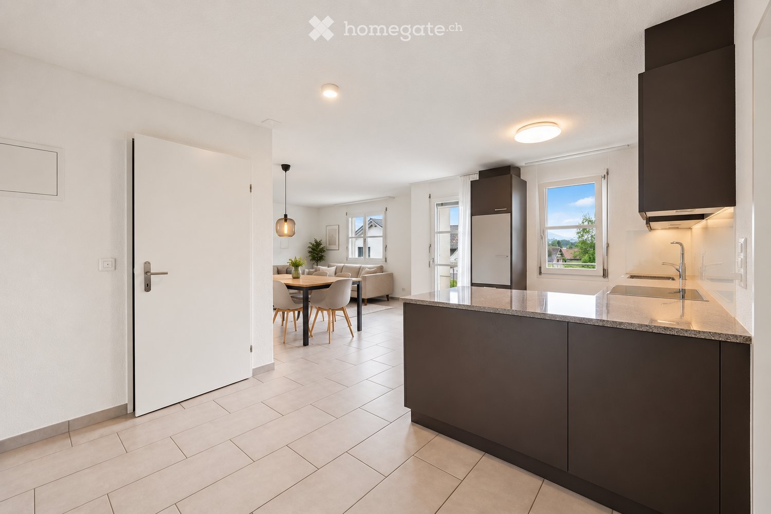 Modern open-plan living and dining area with a kitchen island, sofa, dining table, chairs, and modern kitchen appliances.