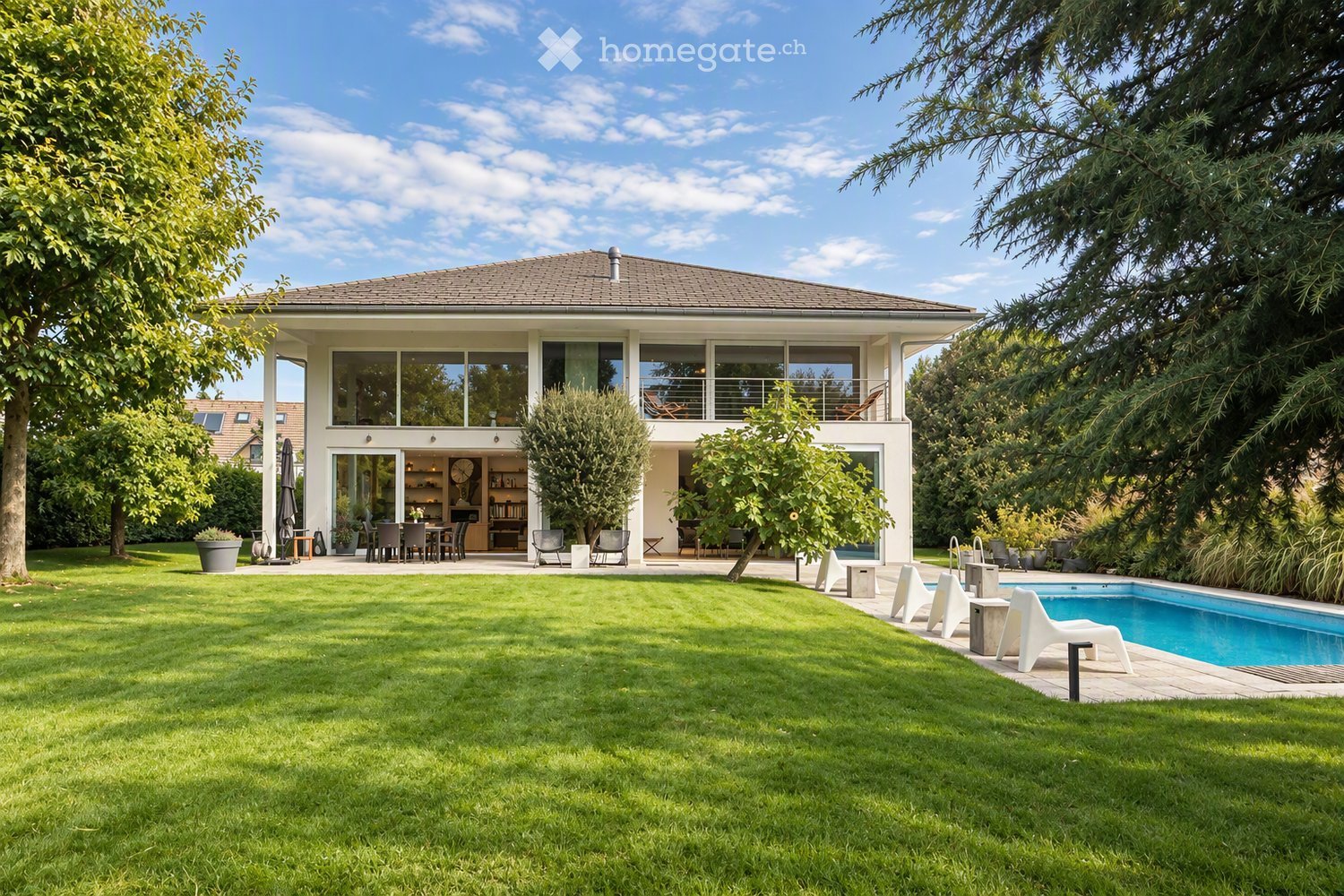 A modern house with a spacious garden, swimming pool, outdoor seating, and a dining area.