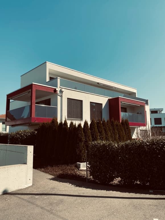 2 story modern house, white and red, glass railing balcony, bushes